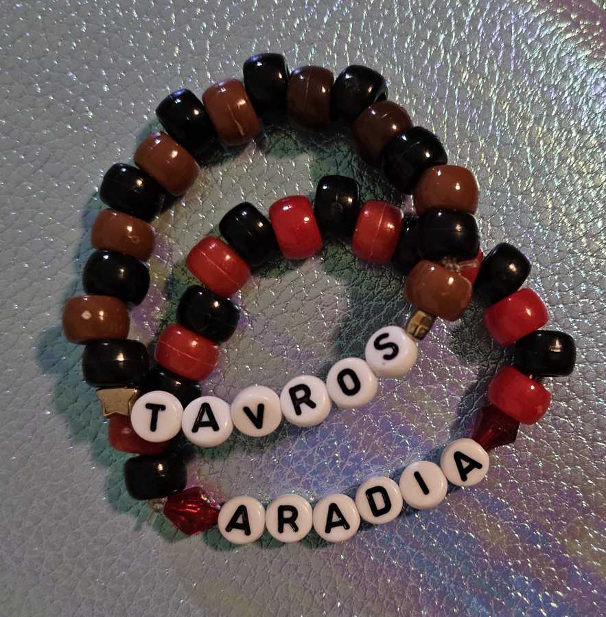 Two simple kandi singles that say 'ARADIA' and 'TAVROS'. The 'ARADIA' single has red and black beads, while 'TAVROS' has brown and black..